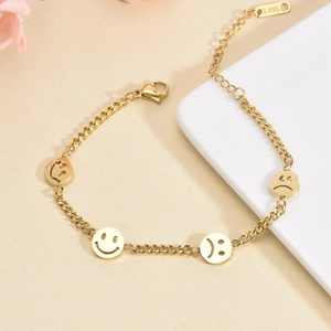 Bracelet doré en acier inoxydable avec breloques emoji sur fond beige élégant
