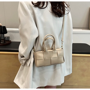 Dettaglio della piccola borsa a mano intrecciata bianco crema con tracolla rimovibile