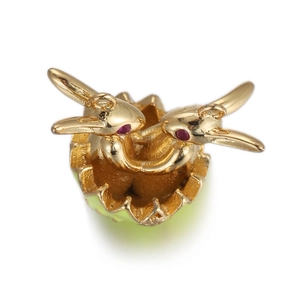 Macro detail of golden dual swan pendant with red gemstone eyes and green shell base