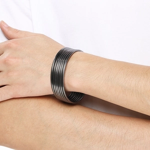 Close-up of minimalist gunmetal grey stainless steel multi-layer cuff bracelet on wrist