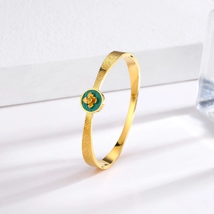 Close-up of vintage gold titanium steel bracelet with green floral clover details