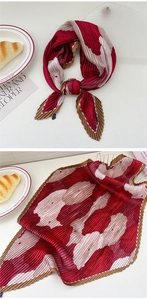 Detailed view of red and brown pleated scarf with abstract floral patterns and textures