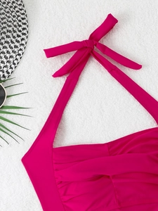 Close-up of rose red halter swimsuit top with elegant ruched texture and bow detail