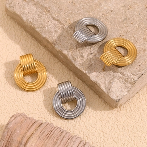 Macro detail of gold and silver textured hoop earrings on a natural stone surface