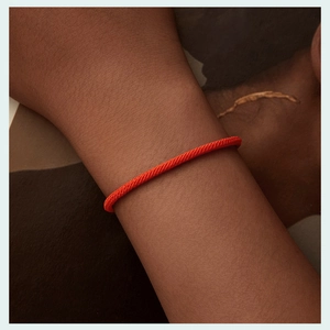 Close-up of a minimalist hand-woven red cord bracelet worn on a female wrist