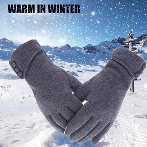 Close-up of gray winter thermal knit gloves for women on a snowy landscape background