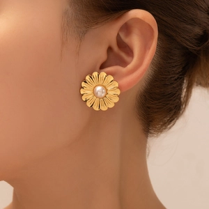Close-up of vintage golden daisy flower earrings with pearl accent on female ear