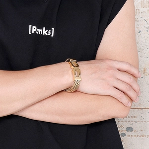 Macro detail of gold link chain bracelet with geometric connectors on model's wrist