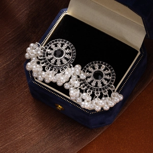 Detail of vintage silver earrings with black gemstones and white pearls on velvet