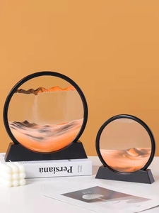 Detail of two circular sand art glass hourglasses in orange and black tones