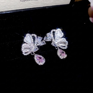 Silver butterfly earrings with white stones and pink teardrop pendant on black velvet