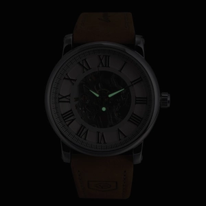 Luminous green hands and markers of a mechanical skeleton watch in a dark setting