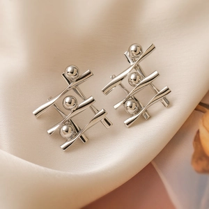 Modern geometric silver-plated earrings with abstract 3D design on beige silk surface