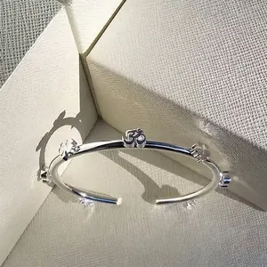 Silver stainless steel open bangle featuring Om symbol and flower charms on jewelry box