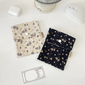 Close-up of floral fabric pouches with resin button closure and woven label detail