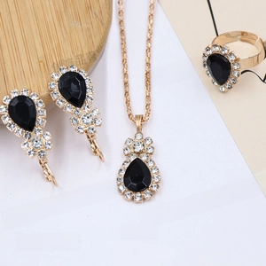 Detail of bridal jewelry set featuring black pear-cut gemstones and diamond halo in gold plating