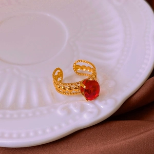 Detail of vintage gold ring with large red zircon on white porcelain and silk