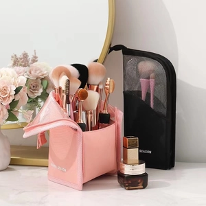Portable mesh makeup brush travel organizers in pink and black on a vanity desk