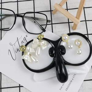 Detail of vintage faux pearl drop earrings displayed on a creative glasses shaped ceramic tray