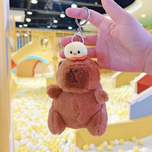 Detail of plush capybara keychain with a small yellow duckling and silver metal clasp