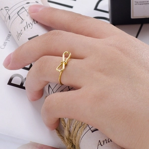 Makroaufnahme eines minimalistischen goldenen Schleifenrings auf dem Finger vor Vintage-Hintergrund