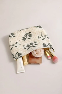 Close-up of floral embroidery on linen cosmetic bag with toiletries and makeup items