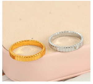 Macro detail of gold and silver vertical textured gear rings on a soft pink leather box