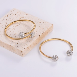 Detailed macro view of gold-plated twisted cable bracelets with crystal pavé balls