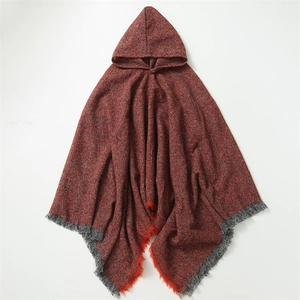 Detail of red knit plaid poncho showing grey tassel fringe and soft fabric texture