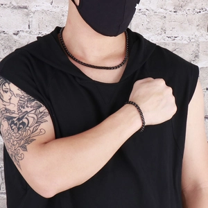 Street style shot of man wearing a set of black beaded necklace and matching bracelet