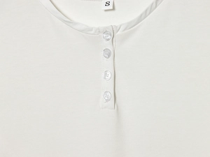 Close-up of white knit dress neckline with a four-button placket and Henley collar