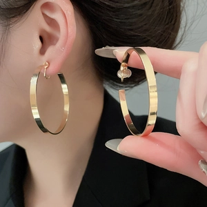Detailed view of large gold hoop earrings with polished flat wide band surface on model