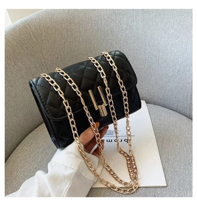 Detail of black quilted chain bag with gold metal cylinder lock and diamond stitching