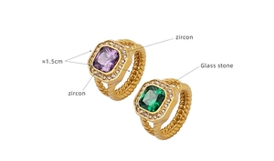 Macro detail of gold plated rings featuring purple zircon and green glass stone inserts