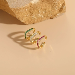 Detailed shot of three V-shaped gold rings with green, white, and red gemstones