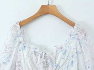 Détail du col carré avec bords à volants et imprimé feuilles bleues sur robe d'été