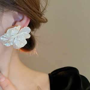 Macro detail of large white shell flower earring with faux pearl on elegant model