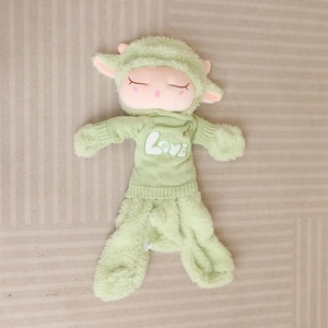 Detailed close-up of a large green sheep plush doll wearing a knit Love sweater