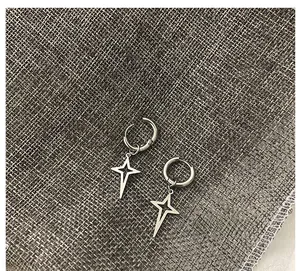 Dettaglio di orecchini a stella d'argento su sfondo di lino grigio con ciondolo a stella