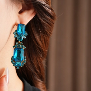 Close-up of vintage geometric blue rhinestone drop earrings worn by a model