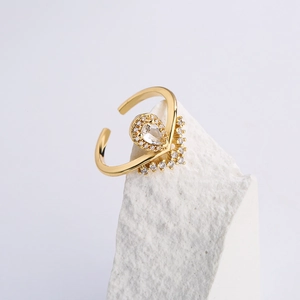 Macro shot of gold plated V-shape ring with teardrop zircon on a white stone base