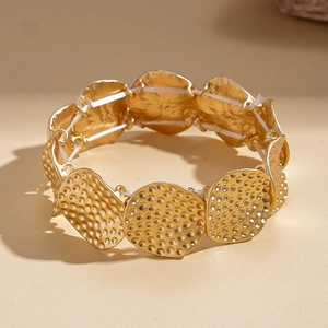 Detailansicht der gehämmerten Goldtextur auf dem geometrischen elastischen Metallarmband