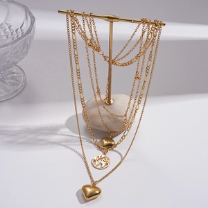 Layered gold necklace featuring heart pendants and a world map charm on T-bar stand