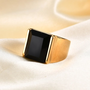 Nahaufnahme eines goldenen Edelstahlrings mit schwarzem Edelstein auf Seidenstoff