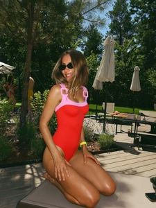 Detail of red and pink contrast one-piece swimsuit with square decorative rings on straps