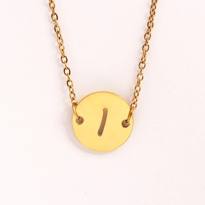 Détail d'un collier doré en acier inoxydable avec pendentif rond et lettre ajourée
