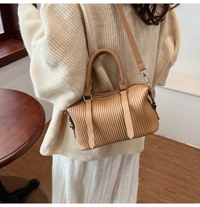 Close-up of light brown pleated leather Boston bag with vertical textures and handle