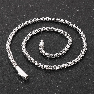 Detailed top view of a polished silver stainless steel box chain necklace on dark surface