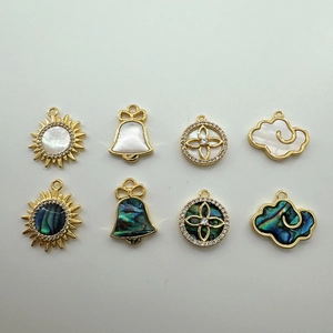 Detail of 18K gold plated shell charms including sun, bell and cloud shapes for DIY jewelry