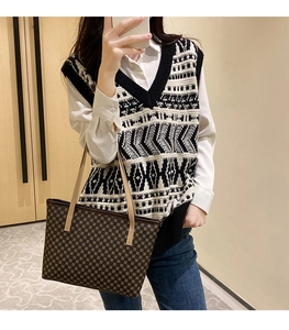 Detail of a brown tote bag with geometric patterns held by a model in a knit vest